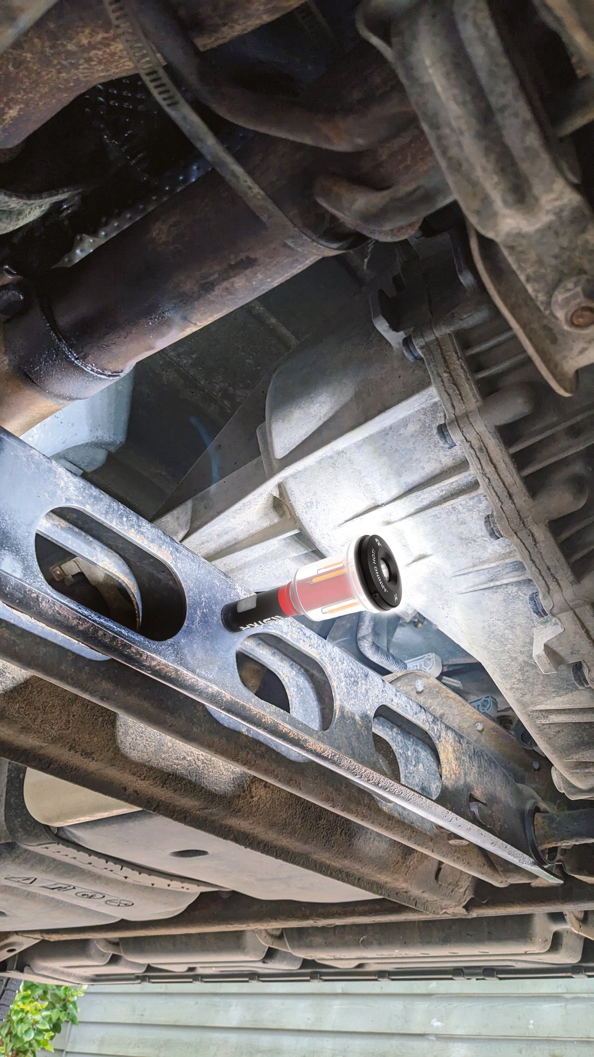 A FLi-MORPHE lantern magnetically stuck to the frame rail under a vehicle for inspection.
