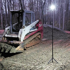 Skid steer loader on a dirt road with a FLi-LITE telescoping tripod light in the foreground