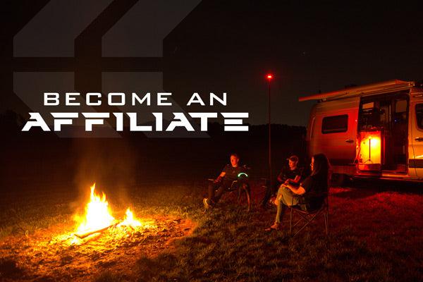 STKR's 'become an affiliate' banner. Image of 3 people sitting in-between a camper van and a campfire at night. Two STKR FLi OVER-LANDER telescoping lights are also lighting up the area.